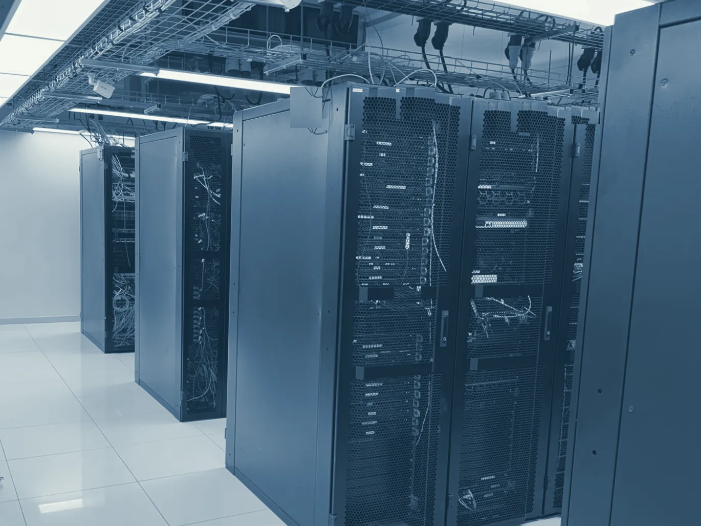 Rack room at the ZGH LR18 data center in Colina: rows of black cabinets, overhead trays carrying fiber and industrial power outlets above each rack